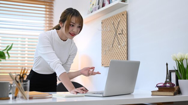 Joven mujer de negocios que se comunica por videoconferencia a través de una computadora portátil durante el trabajo desde casa