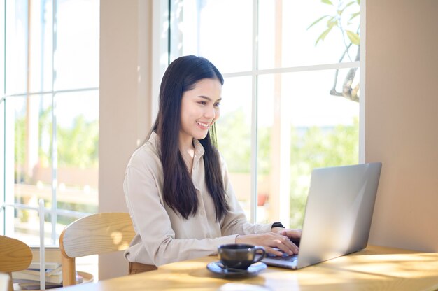 Una joven mujer de negocios que trabaja con su computadora portátil en la cafetería.