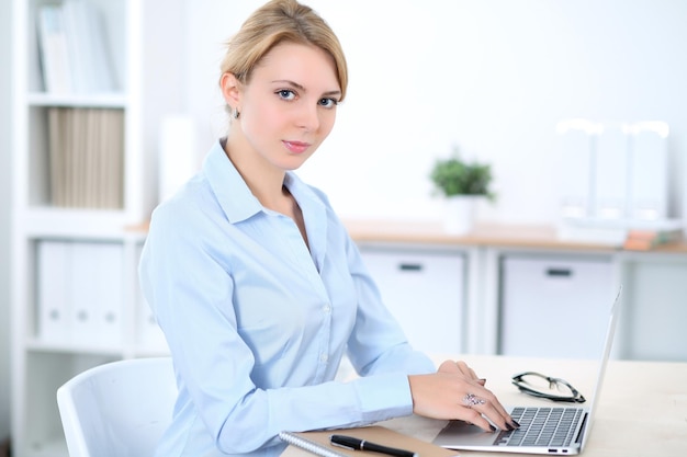 Joven mujer de negocios rubia con laptop en la oficina. Concepto de negocio.