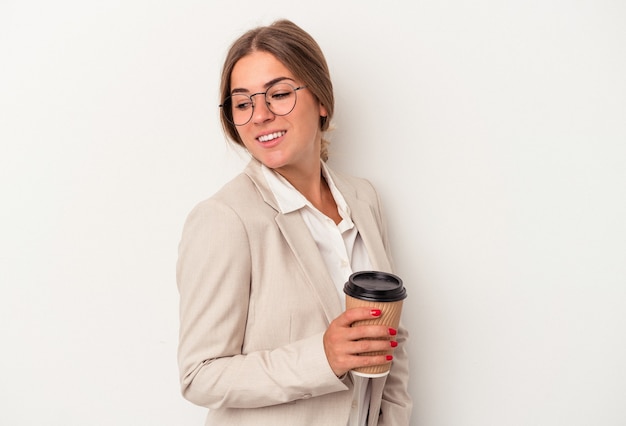 Joven mujer de negocios rusa sosteniendo billetes aislados sobre fondo blanco mira a un lado sonriente, alegre y agradable.