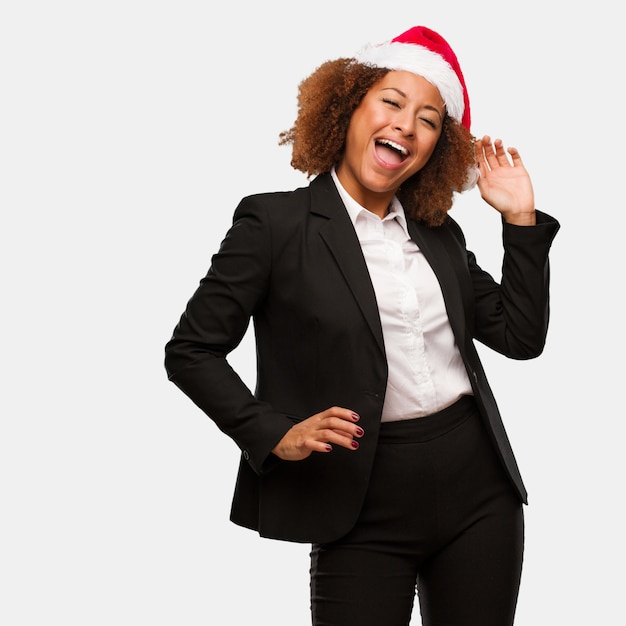 Joven mujer de negocios con un sombrero de santa chirstmas bailando y divirtiéndose