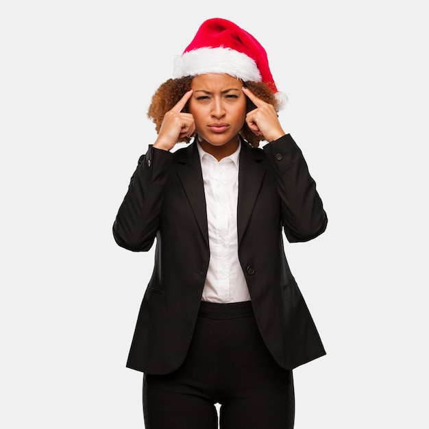 Joven mujer de negocios con un sombrero de santa chirstmas haciendo un gesto de concentración