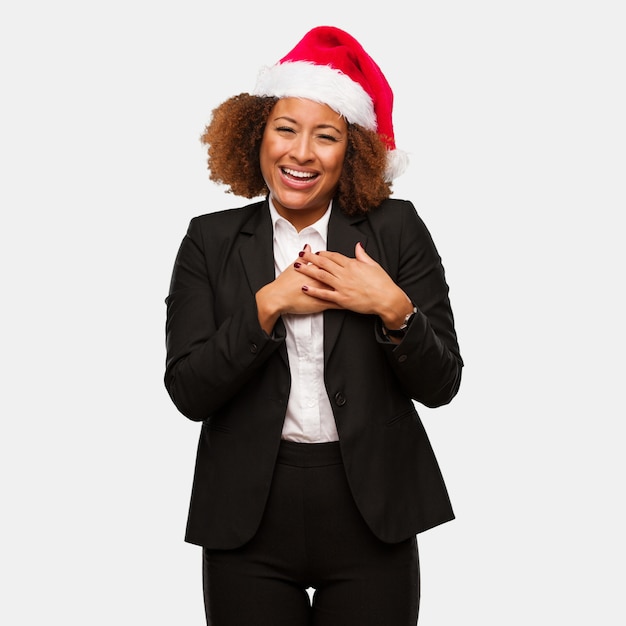 Joven mujer de negocios con un sombrero de santa chirstmas haciendo un gesto romántico