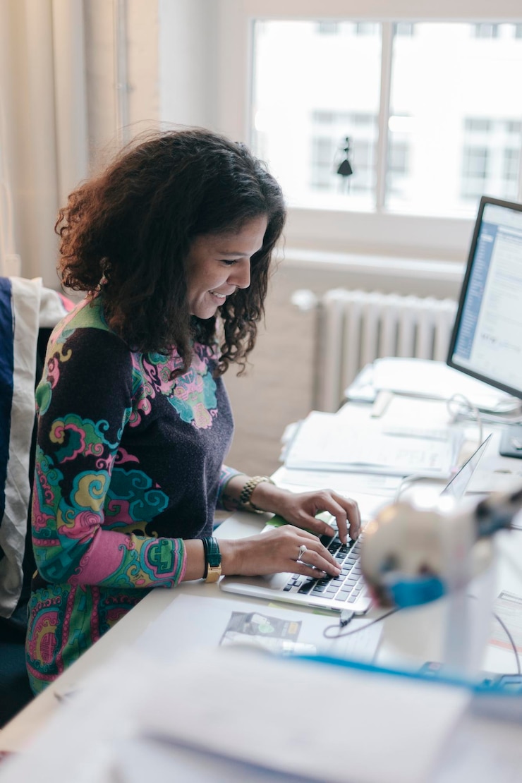 Foto una joven mujer de negocios sonriente escribiendo en una computadora portátil en la oficina