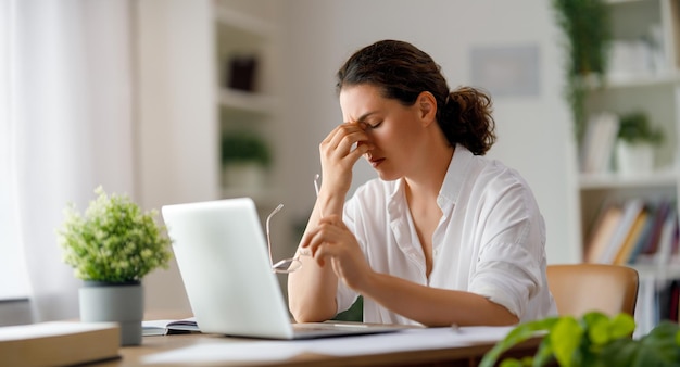 Joven mujer de negocios trabajando en una computadora portátil y con dolor de cabeza