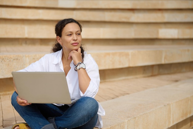 Joven mujer de negocios usando una computadora portátil mientras está sentada en la escalera