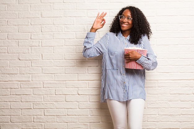 Joven mujer negra alegre y confiada haciendo gesto aceptable, excitada y gritando, concepto de aprobación y éxito