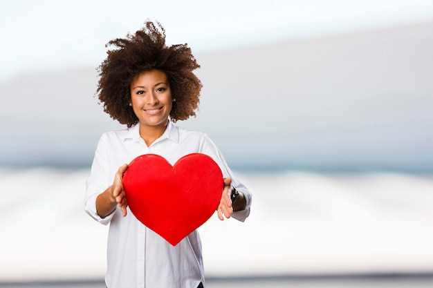 joven mujer negra con forma de corazón rojo