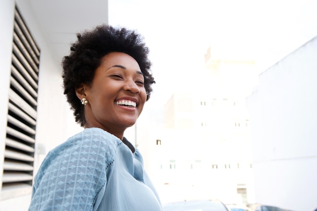 Joven mujer negra de pie al aire libre y sonriente