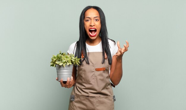 Joven mujer negra que parece enojada, molesta y frustrada gritando wtf o qué te pasa. concepto de jardinero