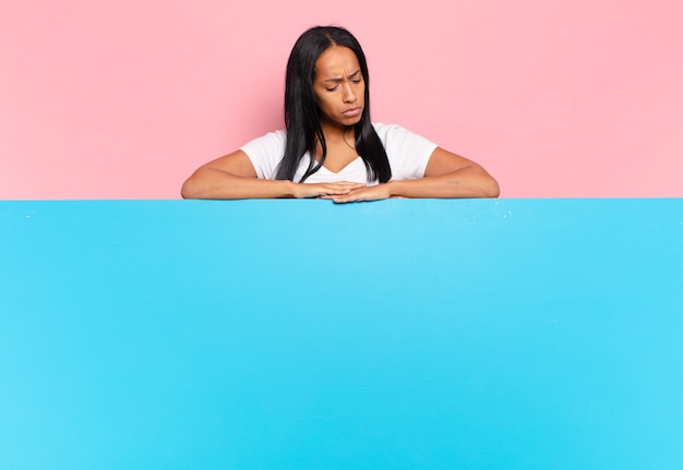 Joven mujer negra que se siente triste, molesta o enojada y mira hacia un lado con una actitud negativa, frunciendo el ceño en desacuerdo. concepto de espacio de copia