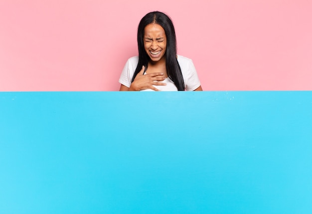 Joven mujer negra riendo a carcajadas de una broma hilarante, sintiéndose feliz y alegre, divirtiéndose. concepto de espacio de copia