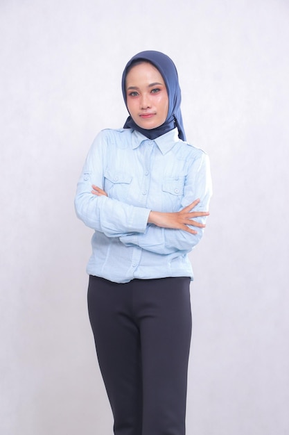 joven mujer de oficina asiática con una camisa azul hijab de pie sonriendo sosteniendo sus brazos cruzados Beauti