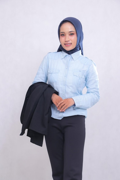 joven mujer de oficina asiática con hijab camisa azul de pie sonrisa alegre manos frente ombligo mangas