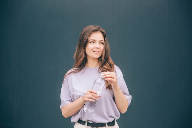 Joven mujer pacífica sosteniendo una botella de plástico con agua clara tsty en ella