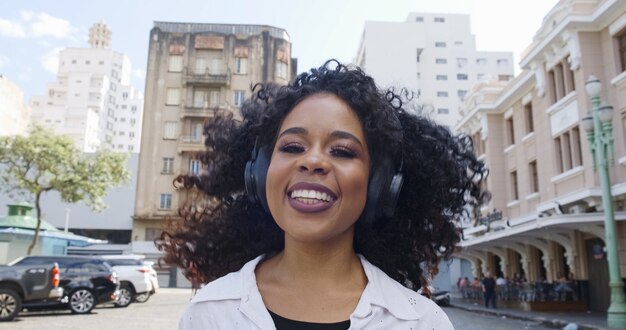 Joven mujer de pelo rizado y auriculares en la calle.