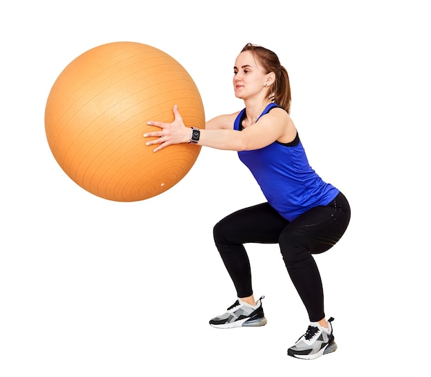 Joven mujer pequeña está entrenando haciendo sentadillas con fyt ball, aislado sobre fondo blanco.