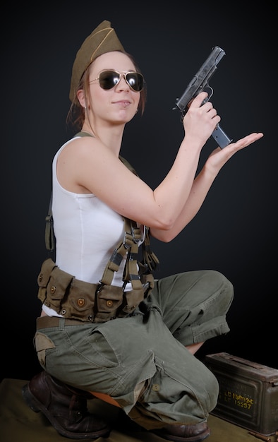 Foto joven mujer posando en uniforme militar y un arma