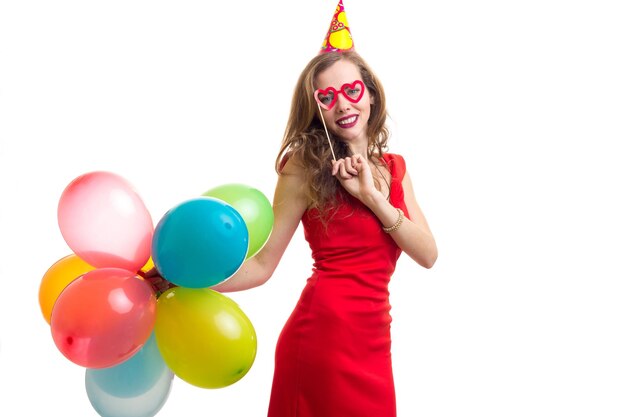 Foto joven mujer positiva celebrando el sombrero con muchos globos de colores y una tarjeta de gafas