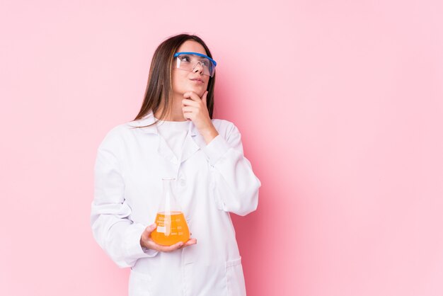 Joven mujer química aislada mirando hacia los lados con expresión dudosa y escéptica