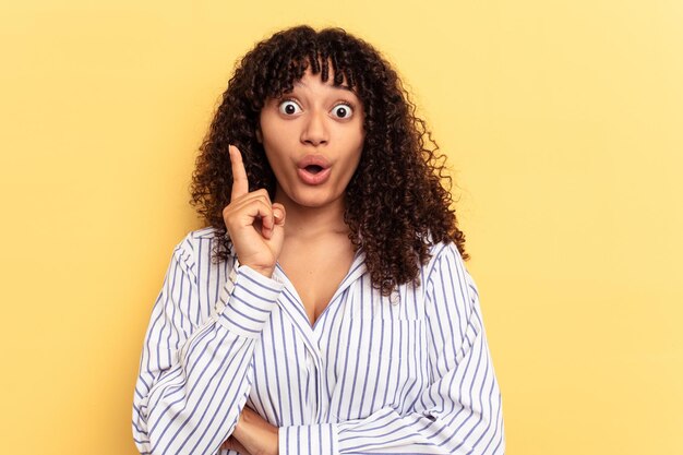 Joven mujer de raza mixta aislada de fondo amarillo que tiene una gran idea concepto de creatividad