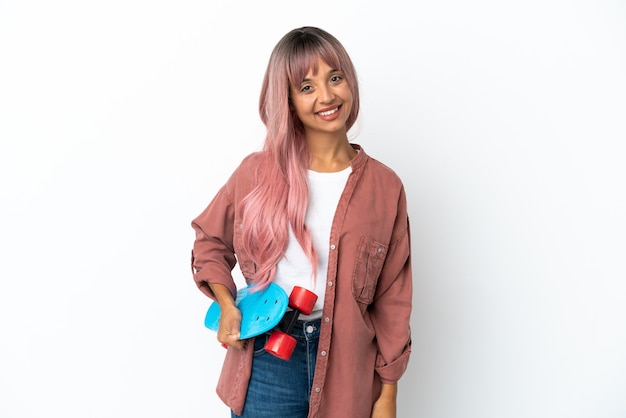 Joven mujer de raza mixta con cabello rosado aislado sobre fondo blanco con un patín