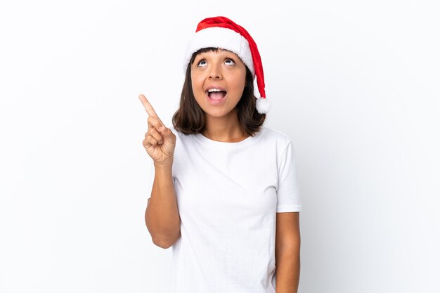 Joven mujer de raza mixta celebrando la Navidad aislado sobre fondo blanco apuntando hacia arriba y sorprendido