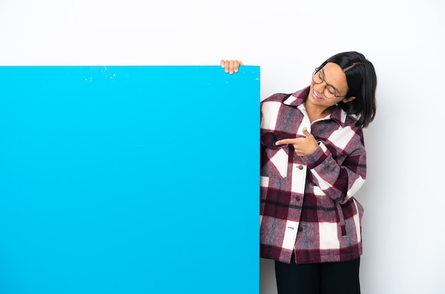 Joven mujer de raza mixta con un gran cartel azul aislado sobre fondo blanco apuntando con el dedo índice una gran idea