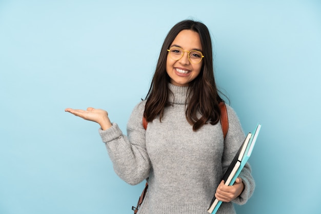 Joven mujer de raza mixta ir a la escuela en la pared azul con espacio en blanco en la palma