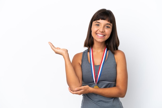 Joven mujer de raza mixta con medallas aisladas de fondo blanco extendiendo las manos a un lado para invitar a venir