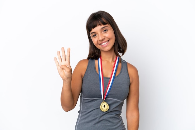 Foto joven mujer de raza mixta con medallas aislado sobre fondo blanco feliz y contando cuatro con los dedos