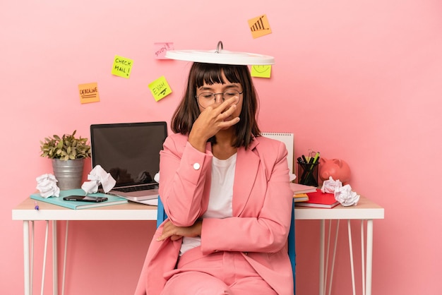 Joven mujer de raza mixta preparando un examen en la habitación sosteniendo una papelera aislada en un fondo rosa