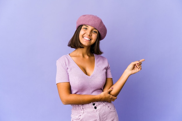 Joven mujer de raza mixta sonriendo alegremente apuntando con el dedo índice.