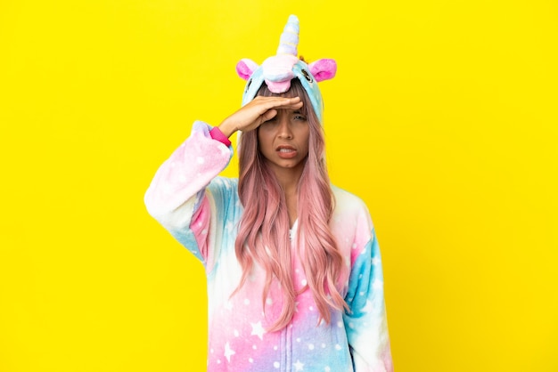 Joven mujer de raza mixta vistiendo un pijama de unicornio aislado sobre fondo blanco mirando lejos con la mano para mirar algo