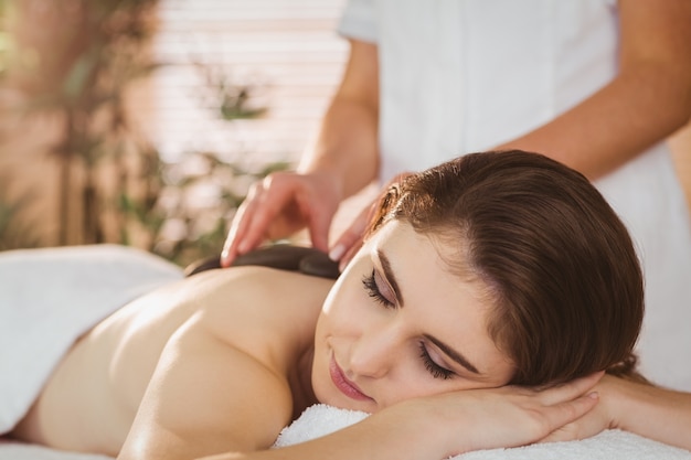 Joven mujer recibiendo un masaje con piedras calientes