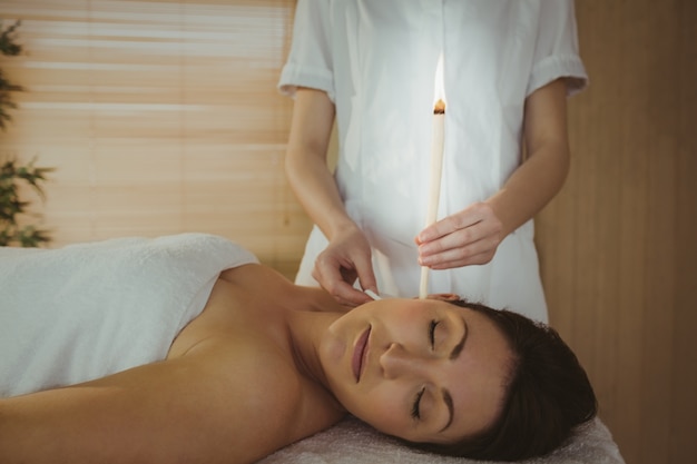 Joven mujer recibiendo un tratamiento de oído candling