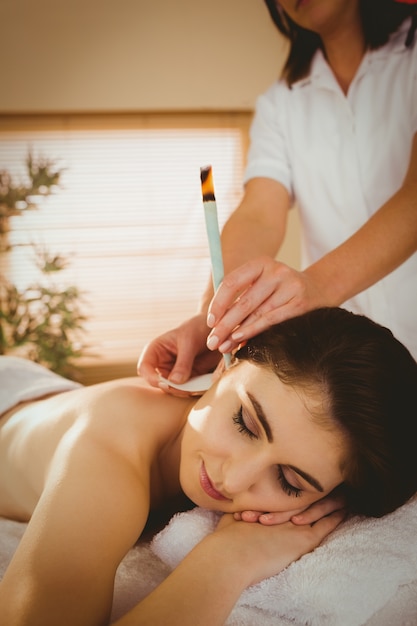 Joven mujer recibiendo tratamiento de oído candling