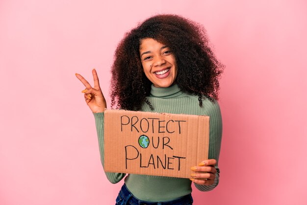 Joven mujer rizada afroamericana alegre y despreocupada mostrando un símbolo de paz con los dedos.