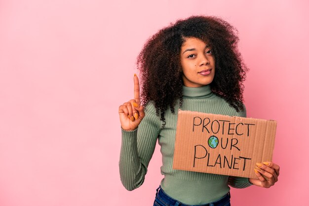 Joven mujer rizada afroamericana mostrando el número uno con el dedo.