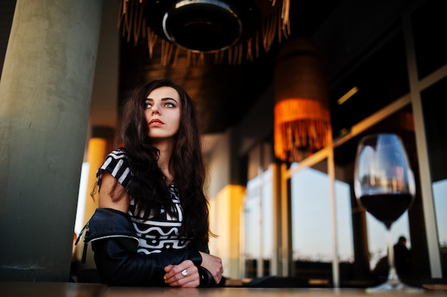 Joven mujer rizada disfrutando de su vino en un bar.