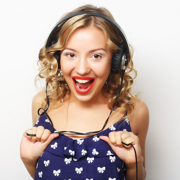 Joven mujer rizada feliz con auriculares escuchando música