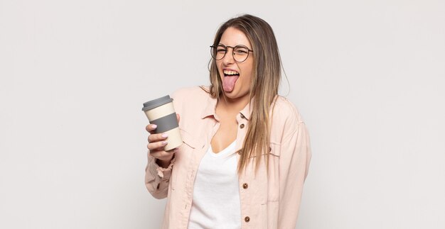 Joven mujer rubia con actitud alegre, despreocupada y rebelde, bromeando y sacando la lengua, divirtiéndose