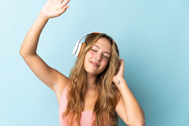 Joven mujer rubia aislada escuchando música y bailando