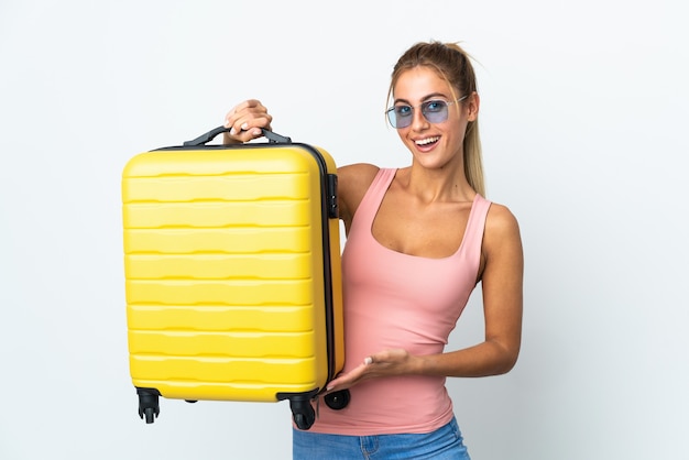 Joven mujer rubia aislada en vacaciones con maleta de viaje