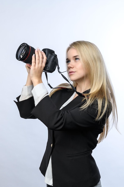 Joven mujer rubia atractiva con cámaras réflex digitales modernas tomando fotos sobre fondo blanco