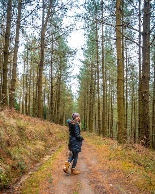 Una joven mujer rubia caminando por un bosque de pinos