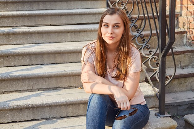 Joven mujer rubia en una camiseta rosa en las escaleras