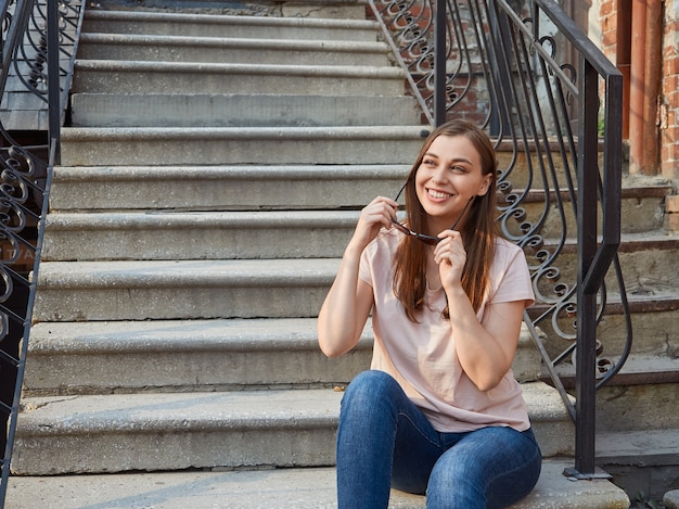 Joven mujer rubia en una camiseta rosa en las escaleras