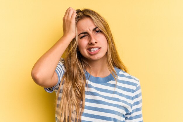 Joven mujer rubia caucásica aislada sobre fondo amarillo cansada y con mucho sueño manteniendo la mano en la cabeza.