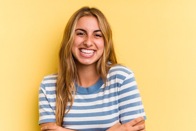 Joven mujer rubia caucásica aislada sobre fondo amarillo riendo y divirtiéndose.